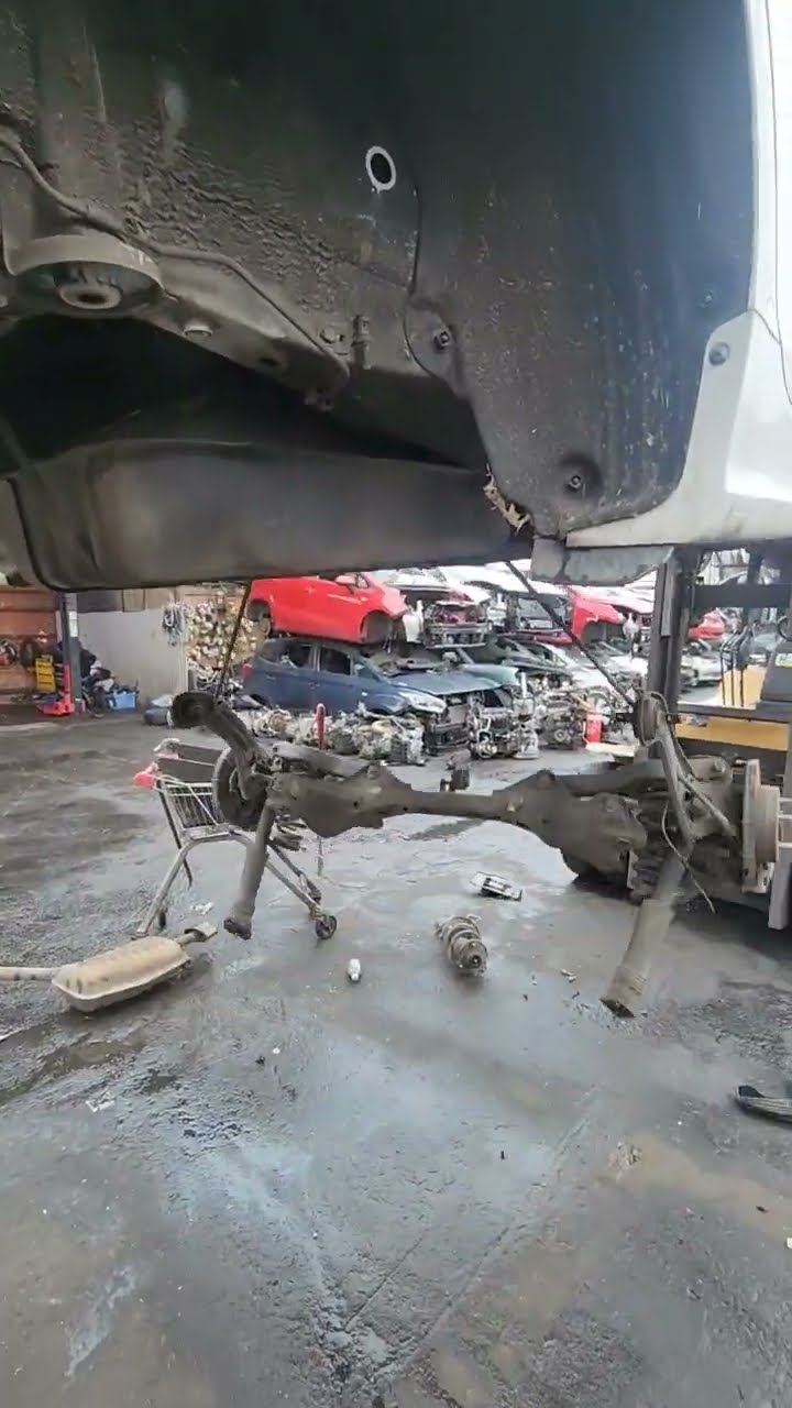 A dismantled suspension assembly beneath a raised car in the workshop.